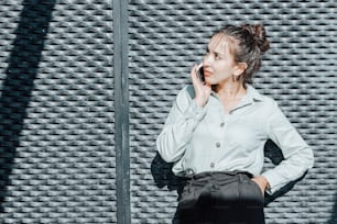 a woman standing in front of a wall talking on a cell phone