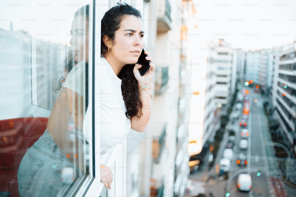 a woman is looking out of a window while talking on a cell phone