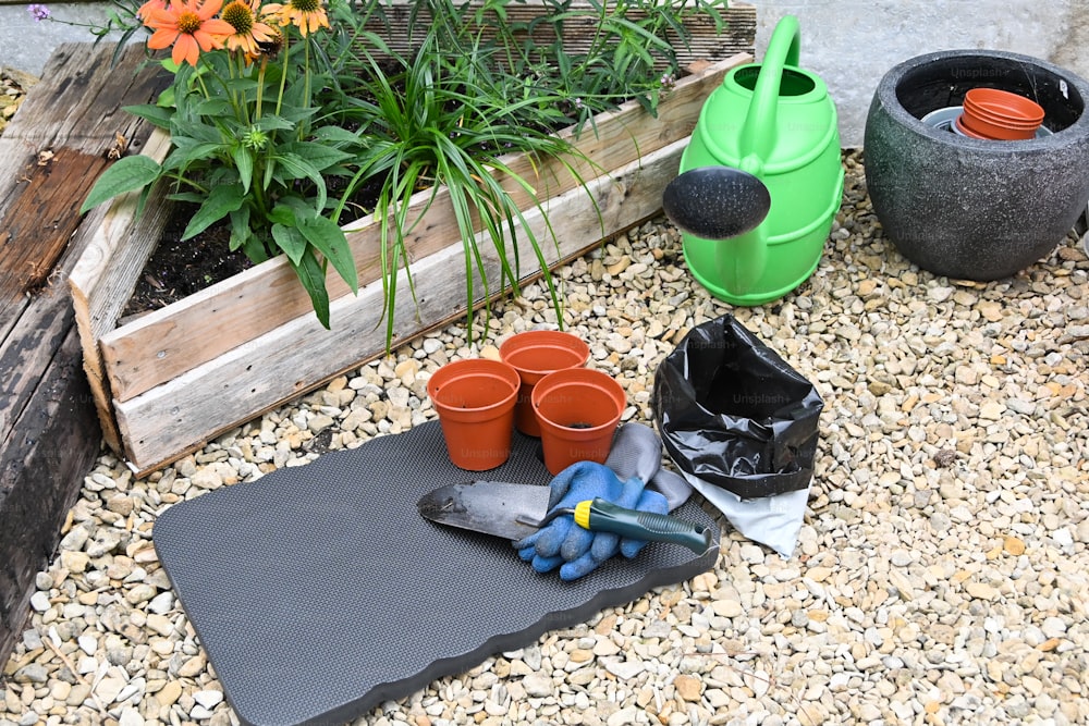 um jardim com vasos e ferramentas de jardinagem no chão