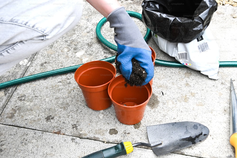a person with gloves and gloves is holding a bucket of dirt