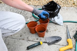 Una persona con guantes y herramientas de jardinería en el suelo