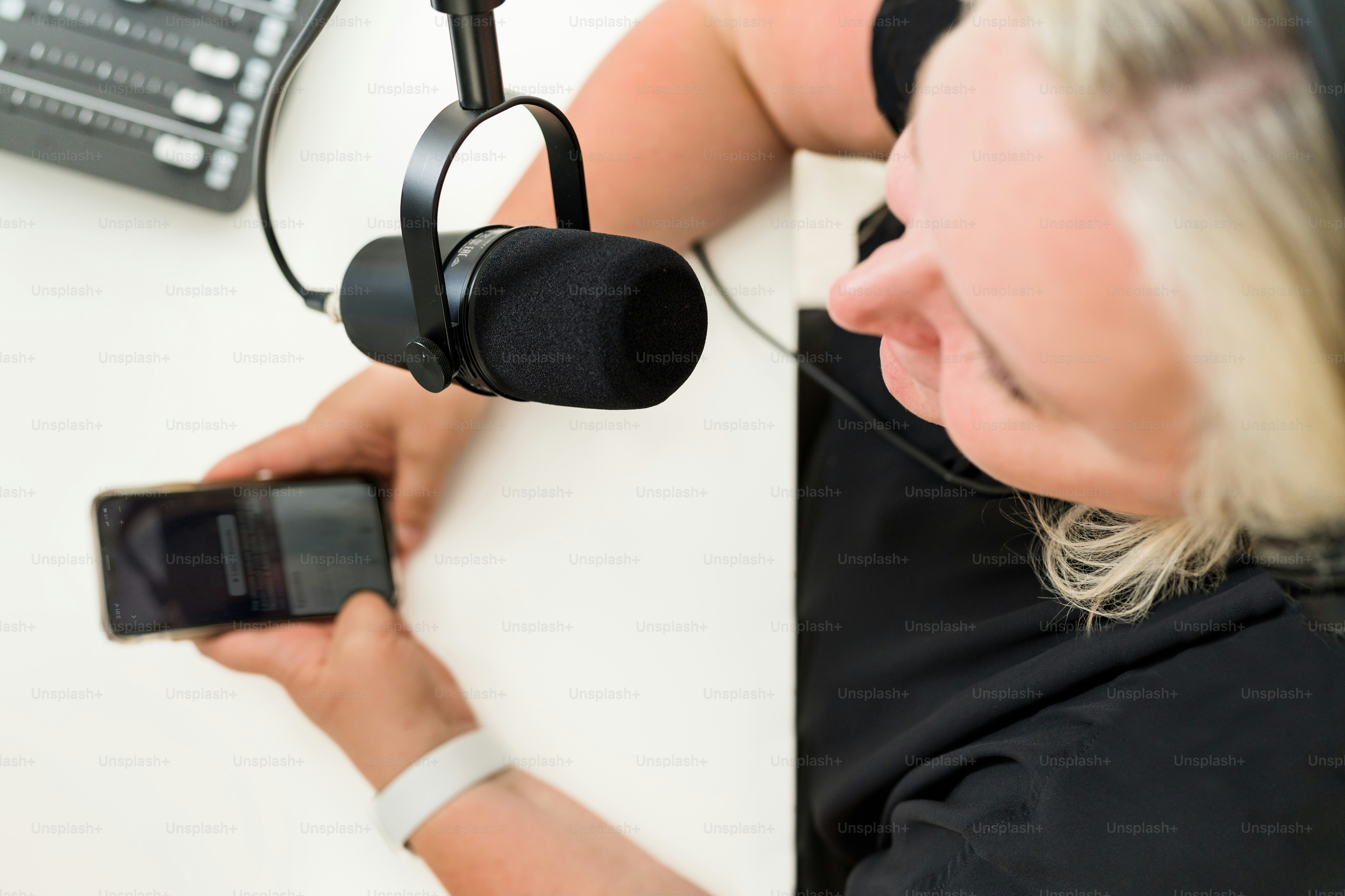 a woman sitting at a table with a microphone and a cell phone