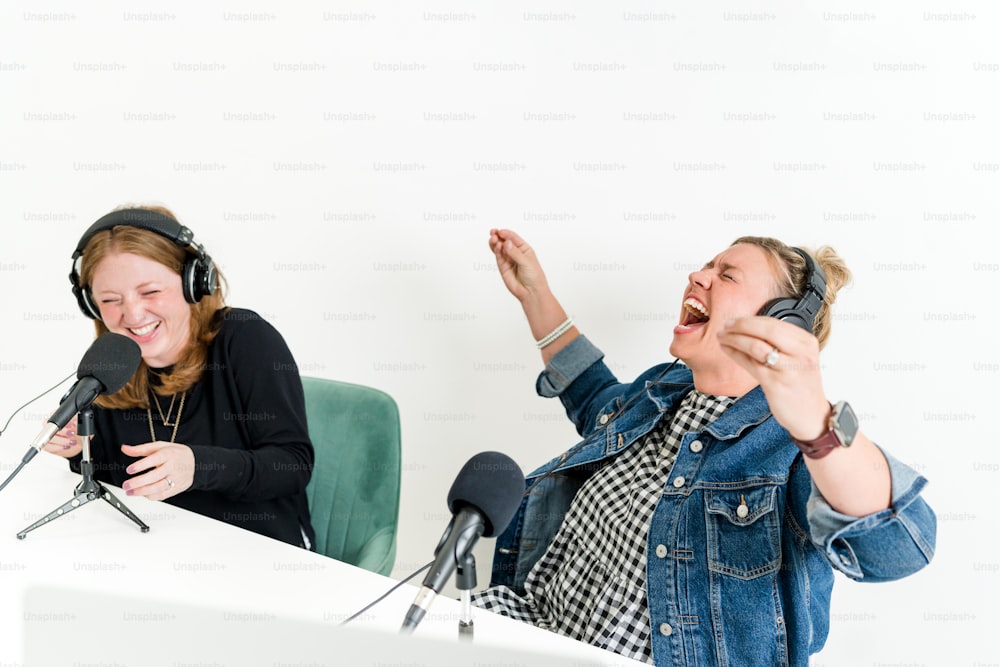 um casal de mulheres sentadas em frente aos microfones