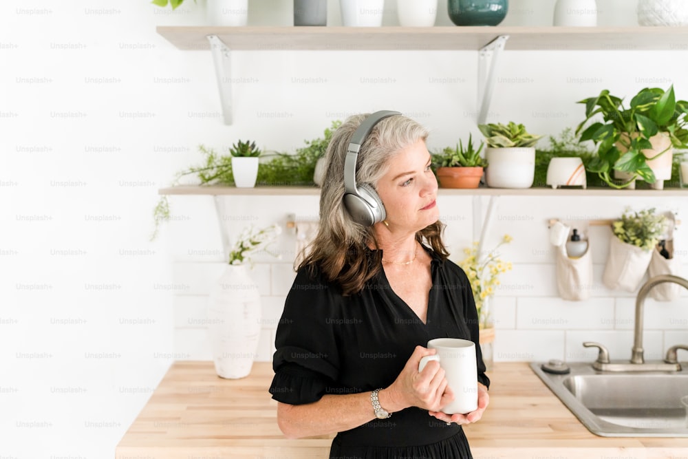Eine Frau mit Kopfhörern, die eine Tasse Kaffee hält