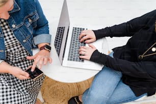 노트북을 사용하여 테이블에 앉아 있는 두 명의 여성