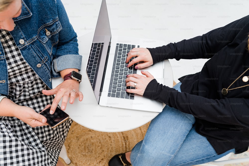 Dos mujeres sentadas en una mesa usando sus computadoras portátiles