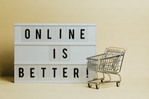 Un carrito de compras junto a un letrero que dice que en línea es mejor