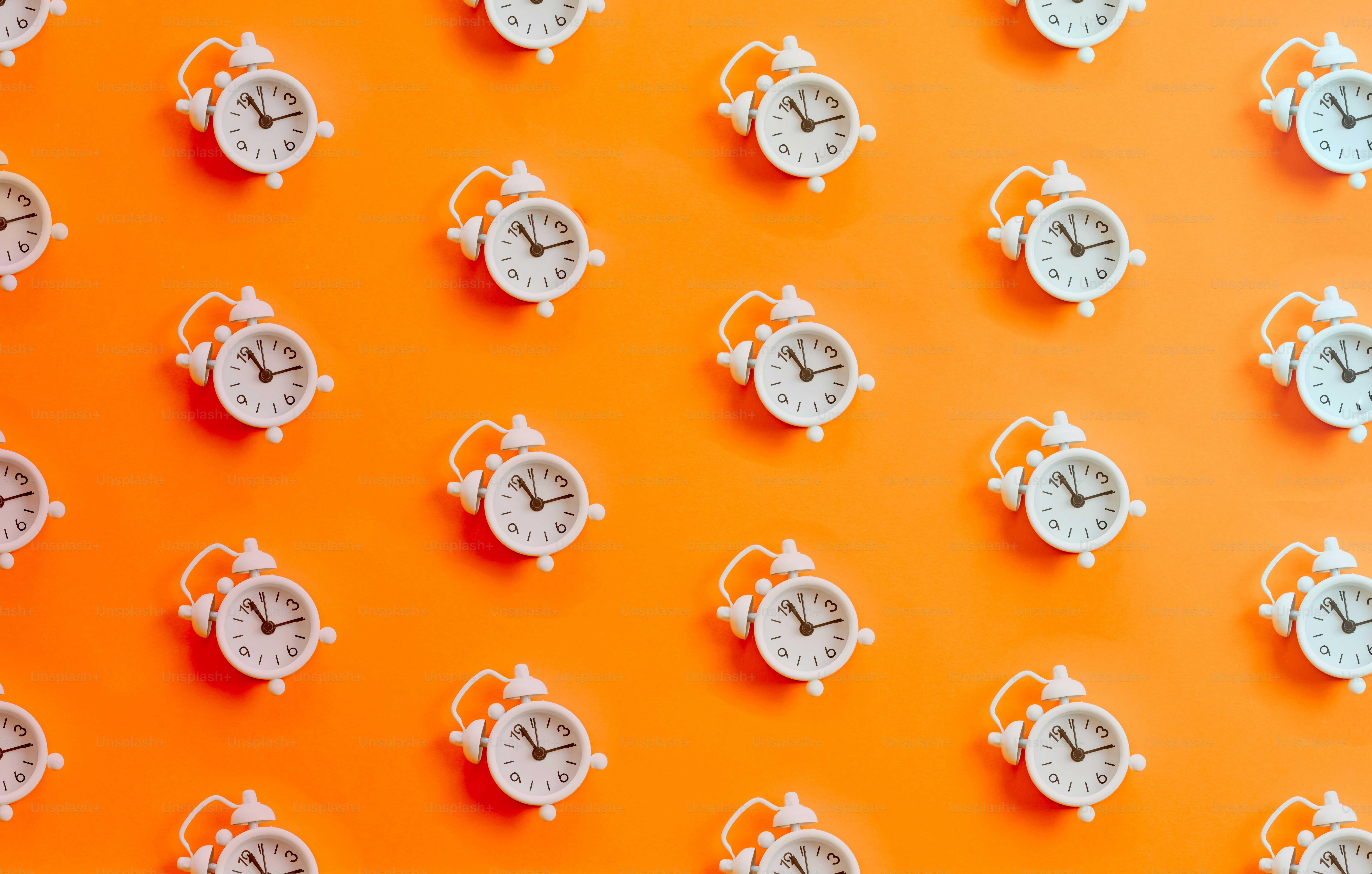 a group of white clocks on a orange wall