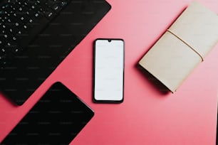 a cell phone and a laptop on a pink surface