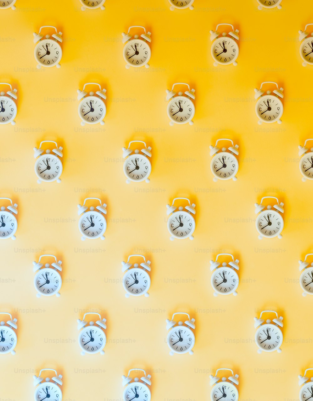 una pared amarilla con muchos relojes