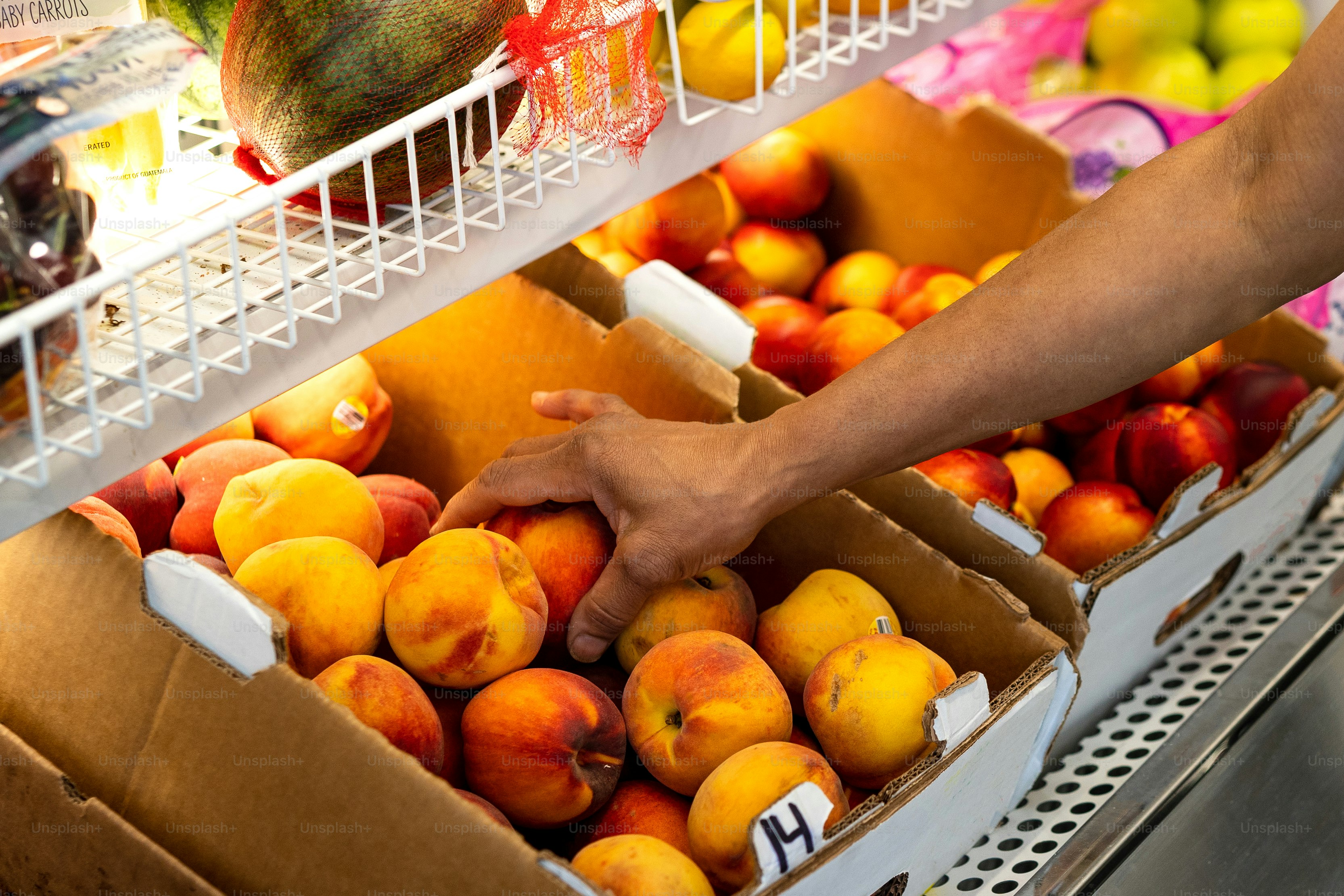 a person reaching for a box of peaches