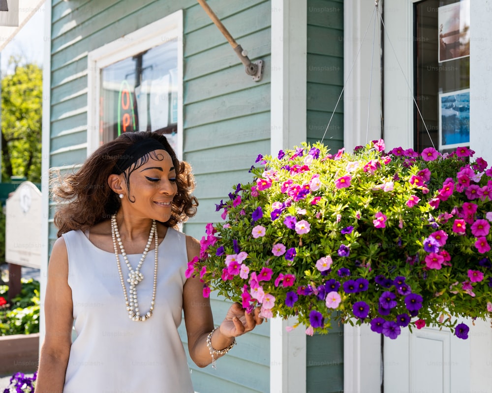 Une femme tenant une plante en pot devant une maison