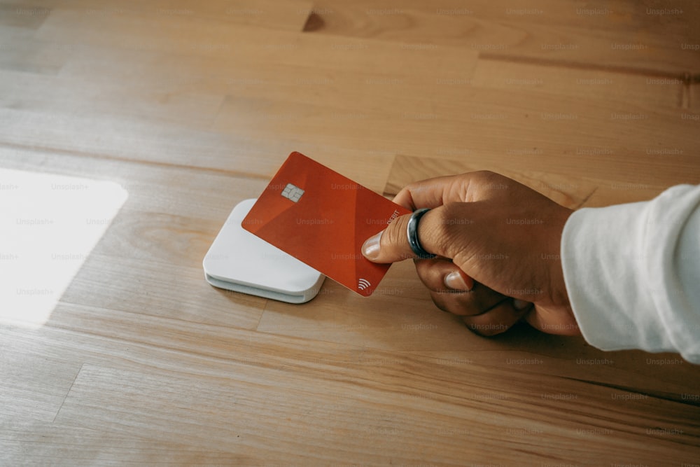 a person holding a red and white credit card