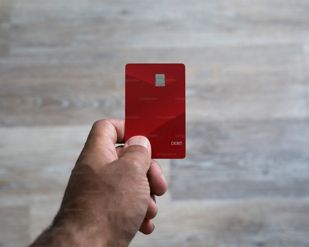 a person holding a red credit card in their hand