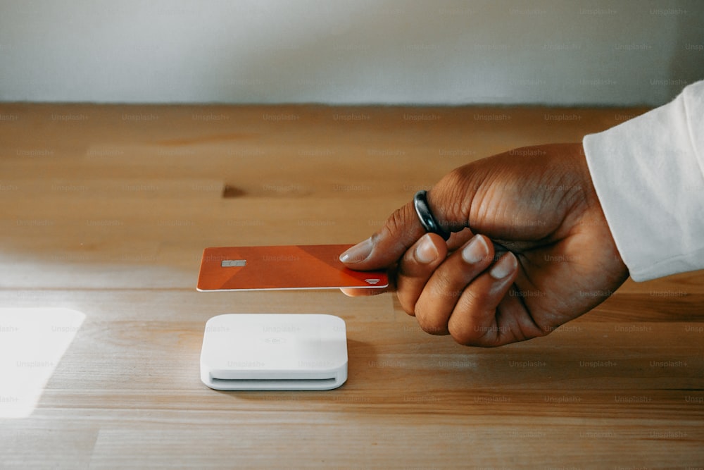 Una persona que sostiene una tarjeta de crédito junto a un teléfono