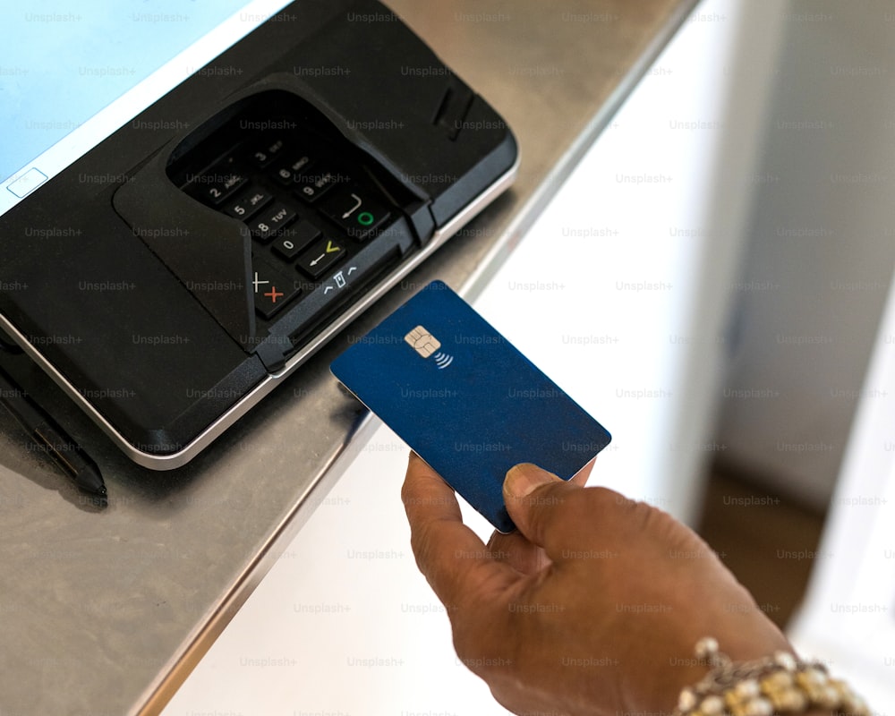 a person holding a credit card in front of a printer