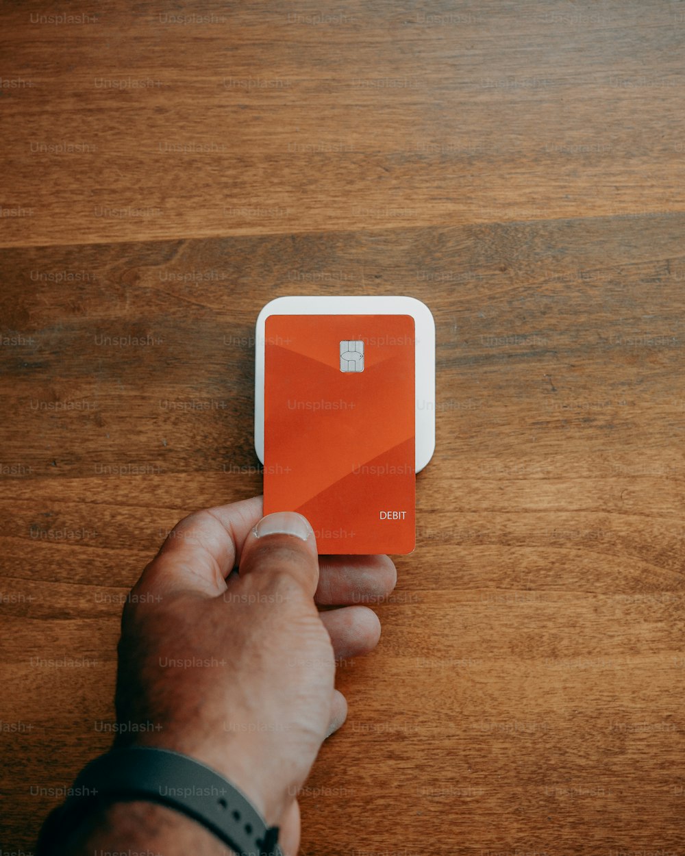 uma mão segurando um cartão laranja em cima de uma mesa de madeira