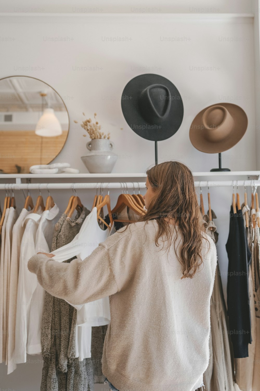 Une femme debout devant un porte-chapeaux