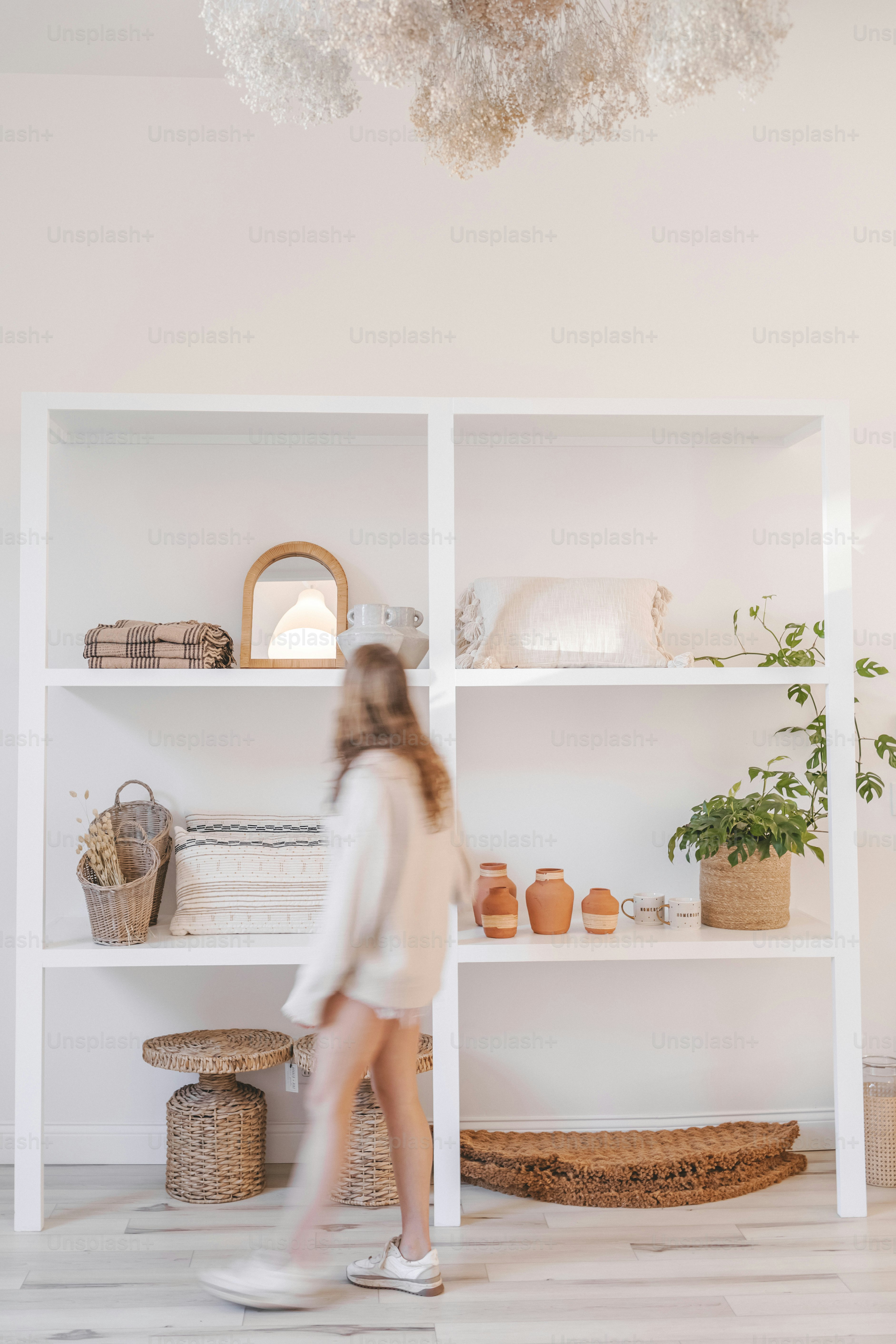 a woman walking in front of a white shelf