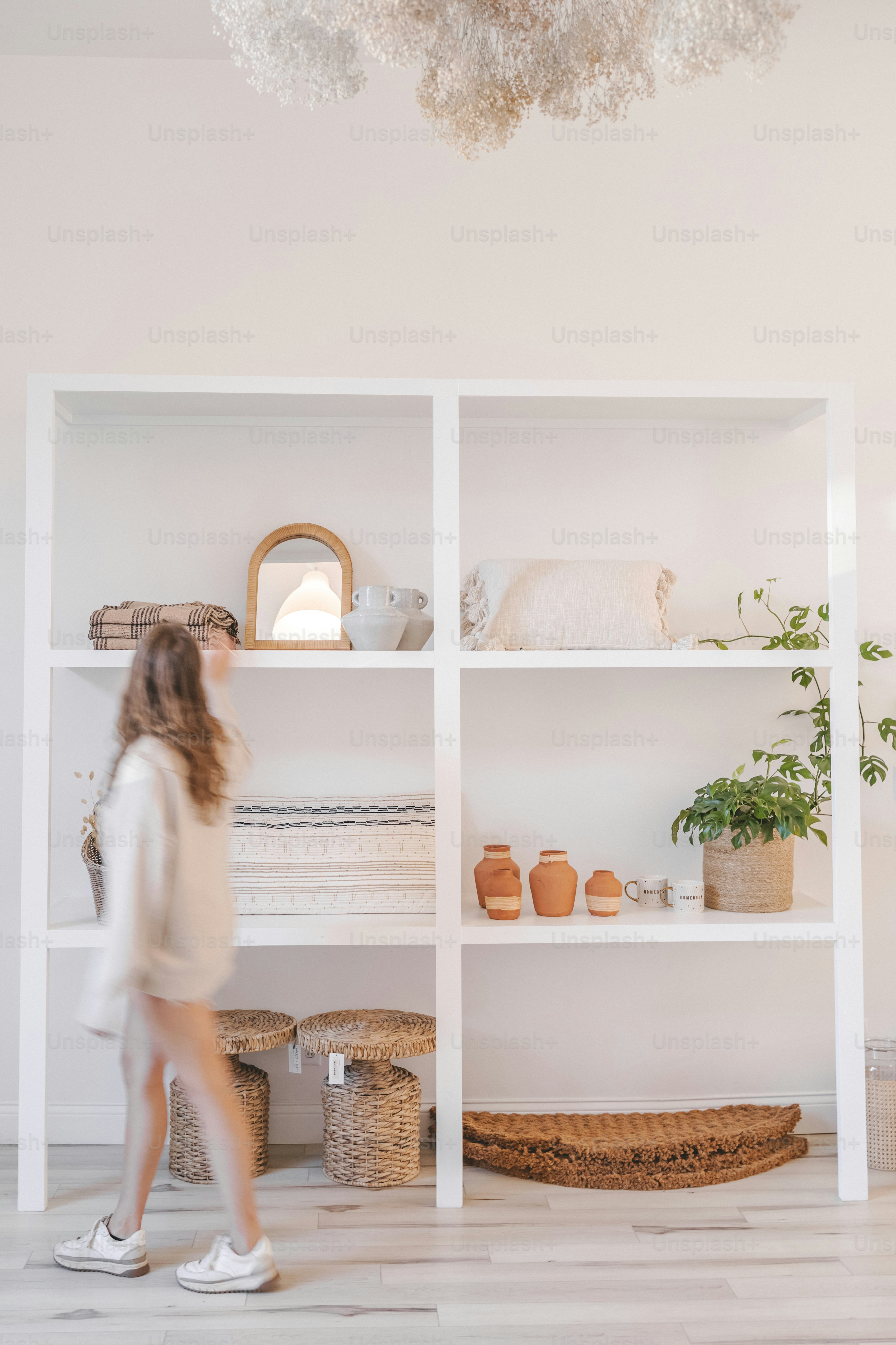 a woman walking in front of a white shelf