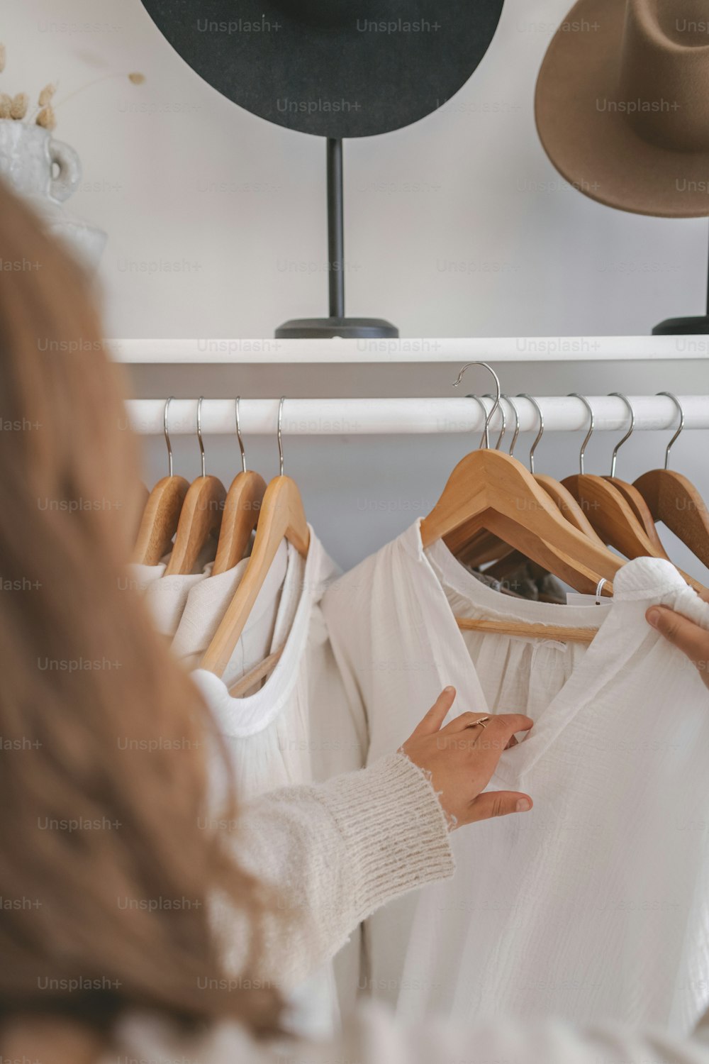 a woman looking at a white shirt on a rack