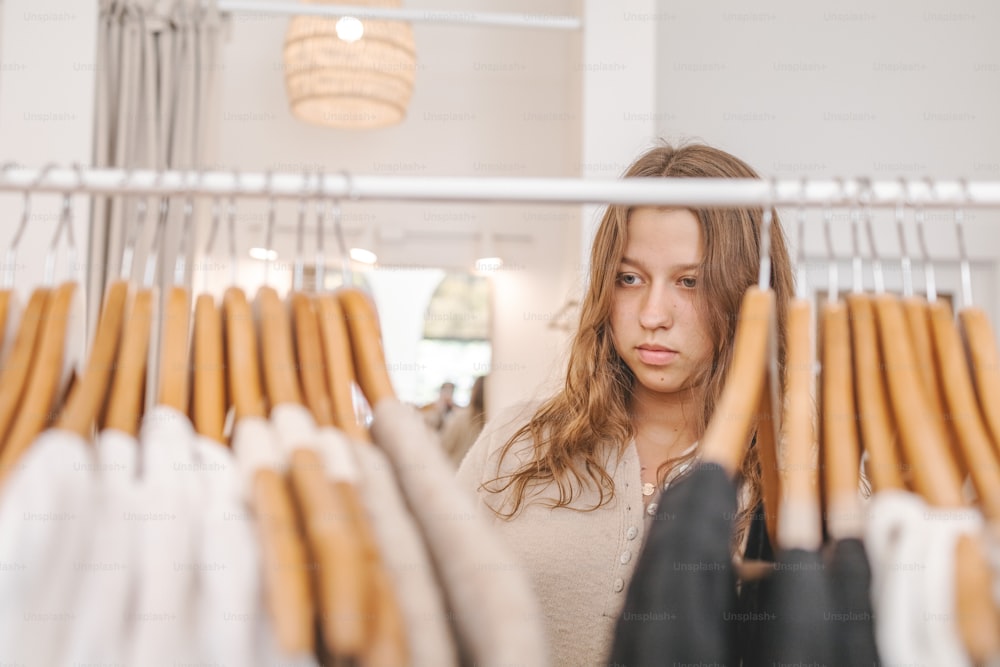 Una mujer mirando la ropa colgada en un estante