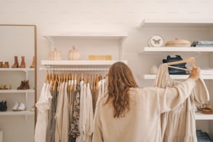 uma mulher em pé em frente a um rack de roupas
