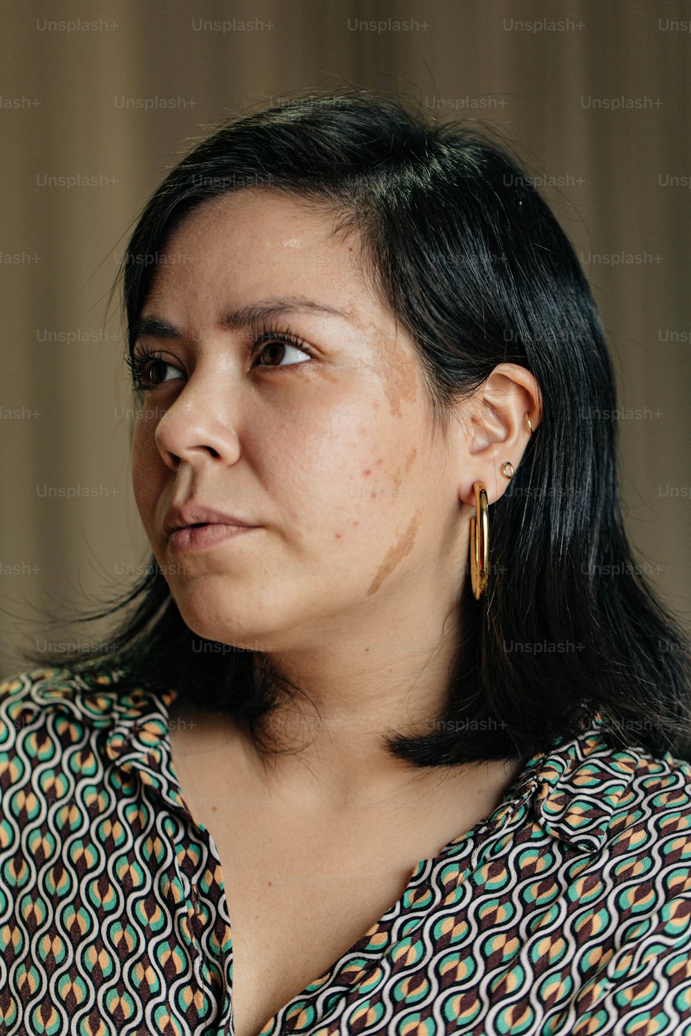 a woman in a patterned shirt looking off into the distance