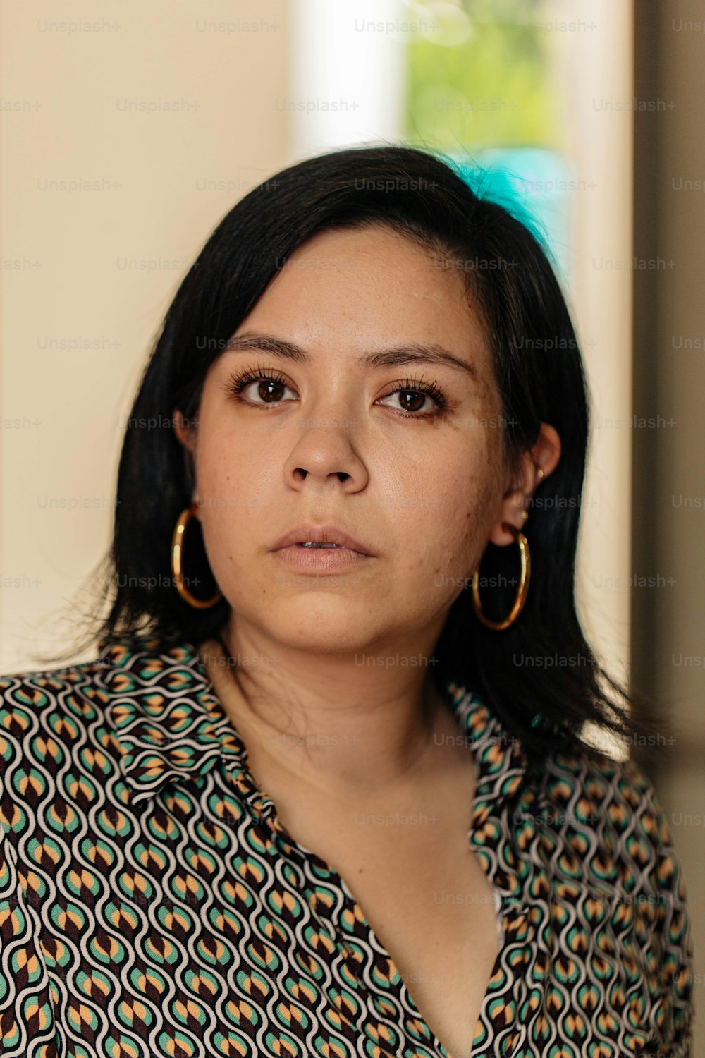 a woman in a patterned shirt looking at the camera