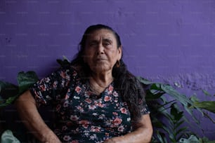 a woman sitting in front of a purple wall