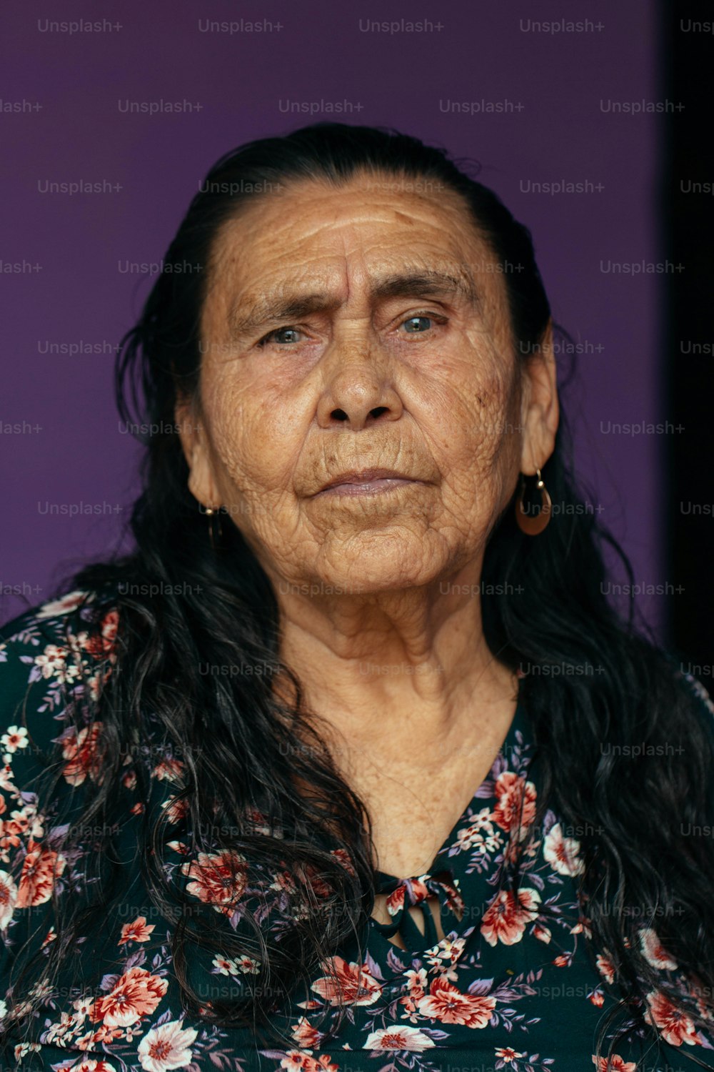 an old woman with long hair wearing a floral shirt