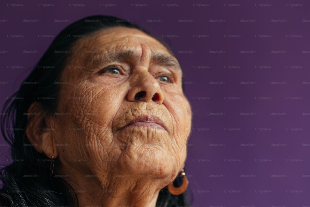Una anciana mirando hacia arriba con un fondo púrpura