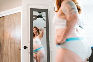 a woman in underwear looking at herself in the mirror