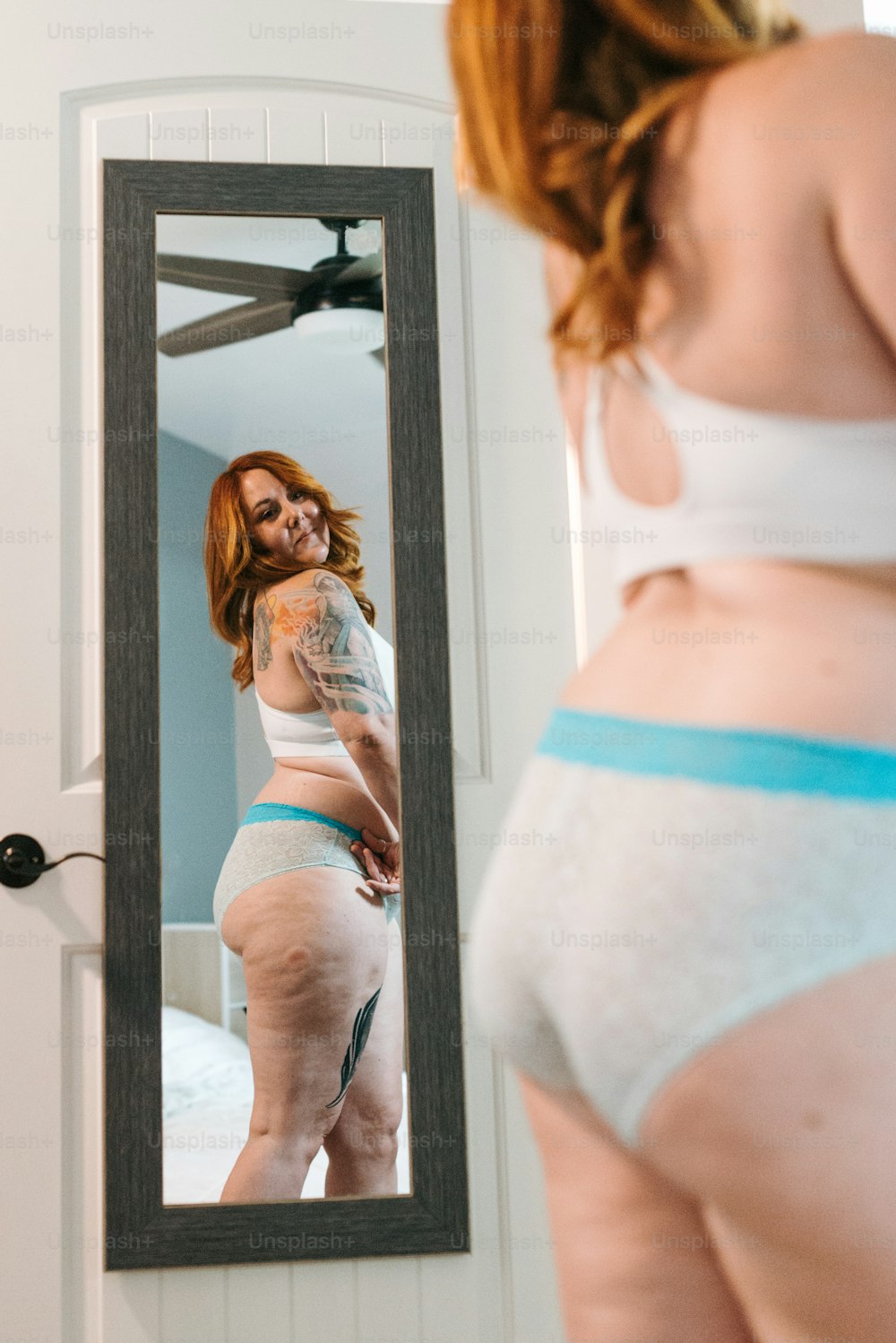 a woman in underwear looking at herself in a mirror