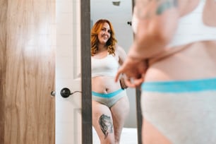 a woman in a white top and blue panties looking at herself in a mirror