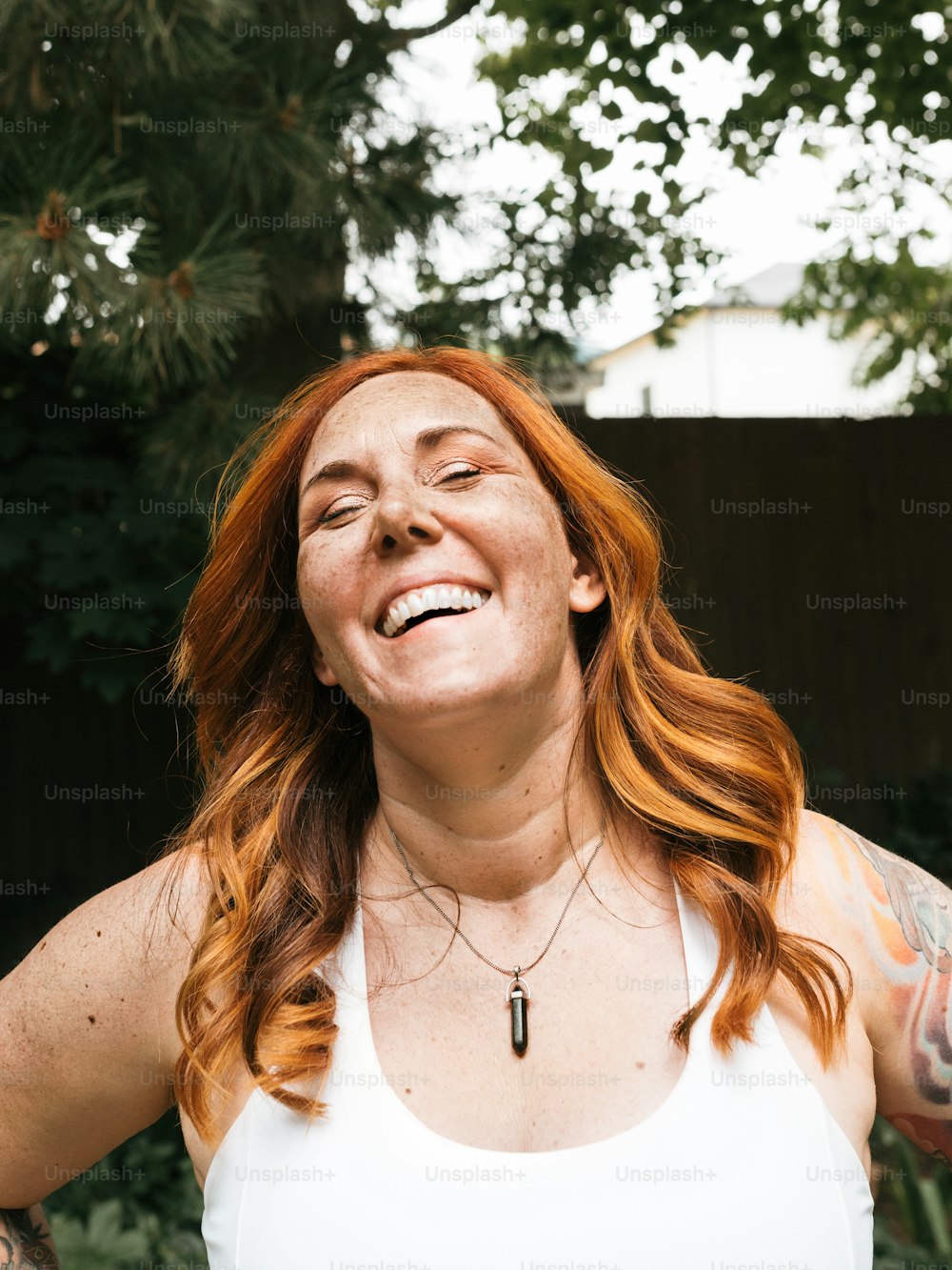 Une femme aux cheveux roux et aux tatouages souriante