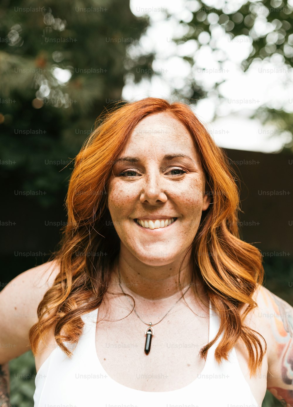 a woman with red hair wearing a white tank top