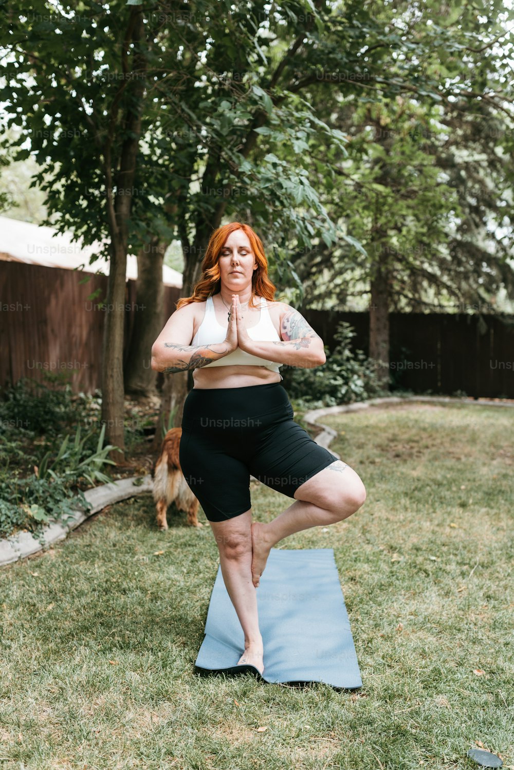 Eine Frau, die auf einer Yogamatte in einem Garten steht