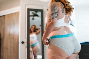 a woman in a white bra and blue panties looking at her reflection in a mirror