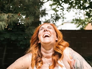 a woman with red hair and tattoos laughing