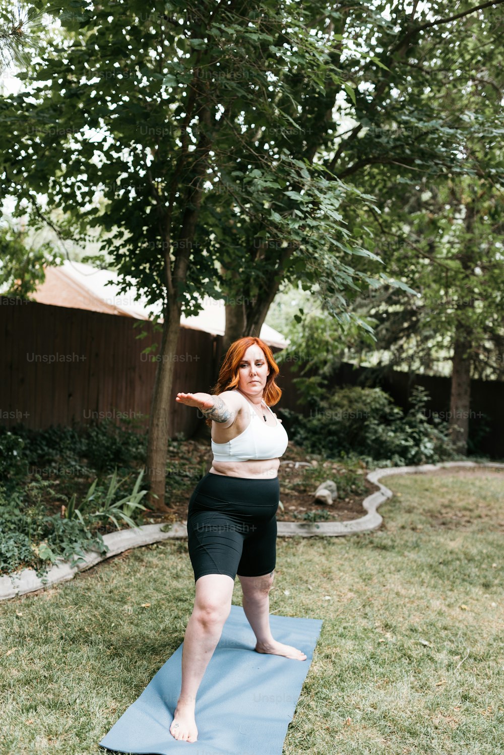 a woman standing on a yoga mat in a yard