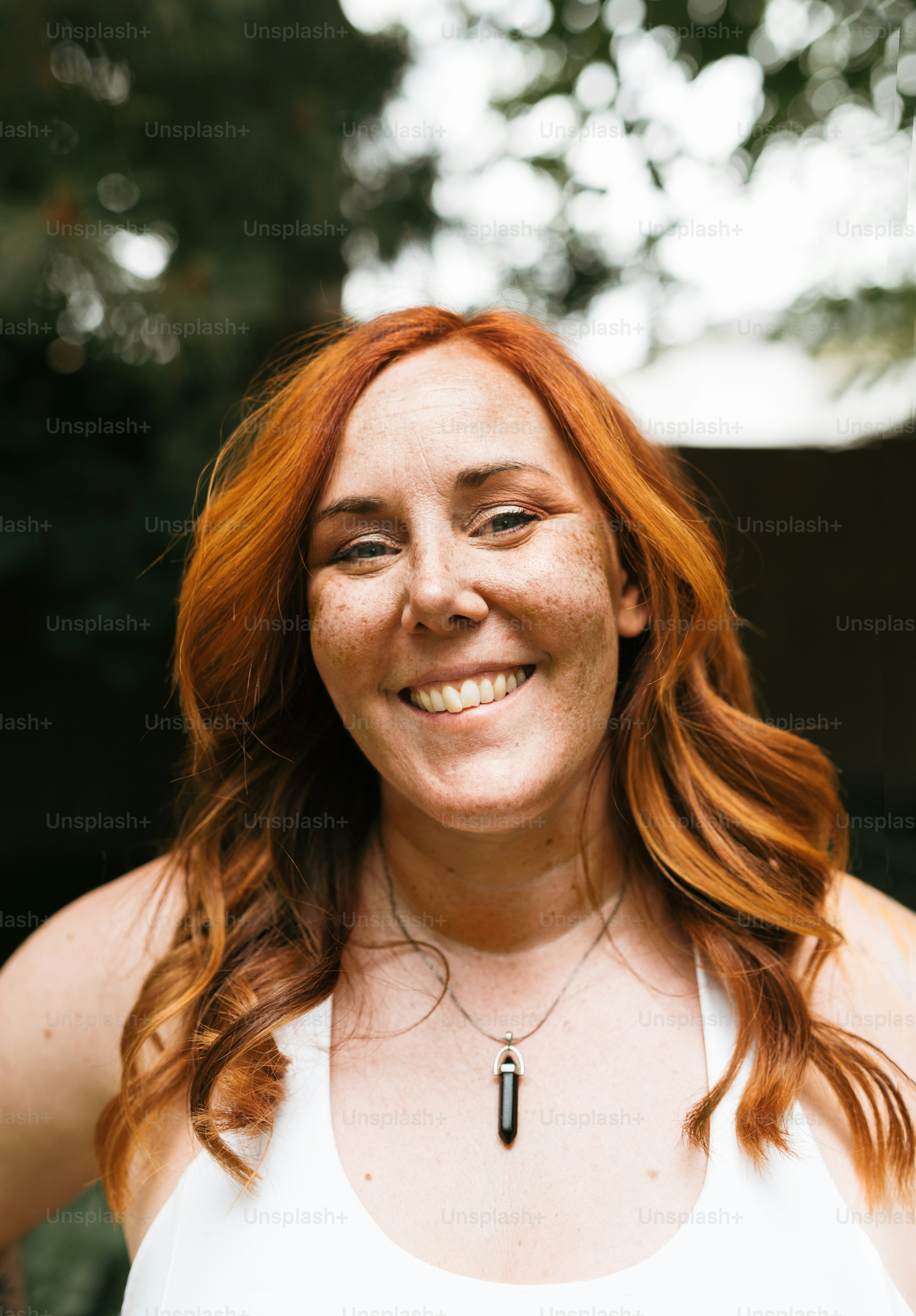 Une femme aux cheveux roux sourit à la caméra