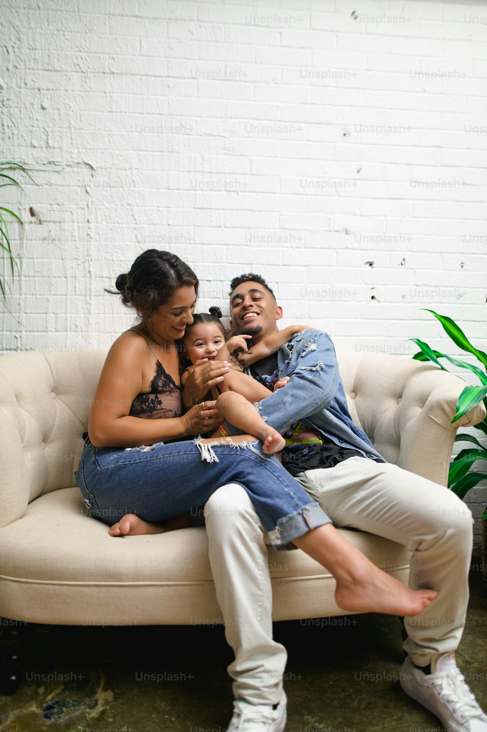 a man and woman sitting on a couch with a baby