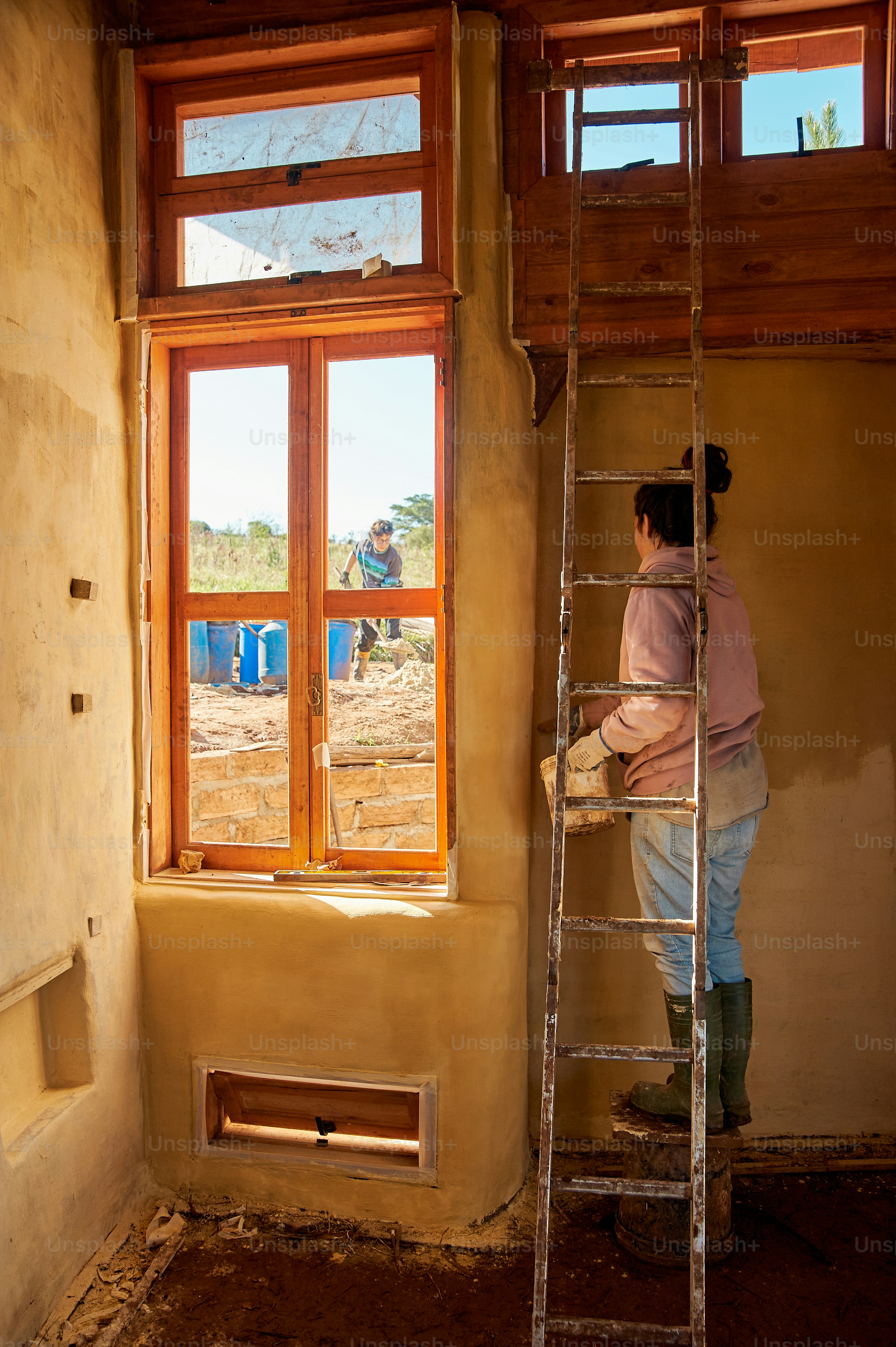 a woman standing on a ladder in front of a window