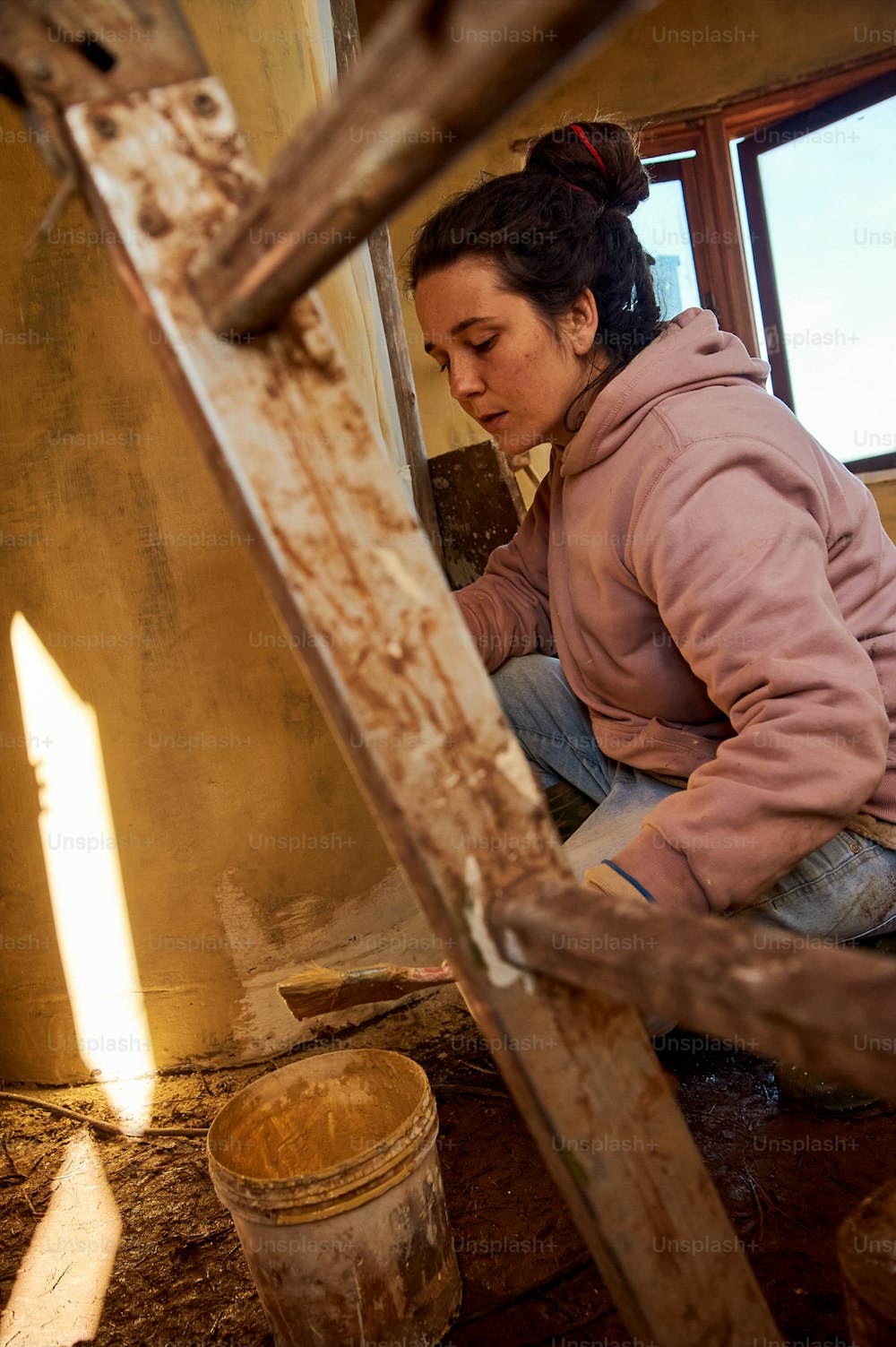 a woman sitting on the floor working on a piece of wood