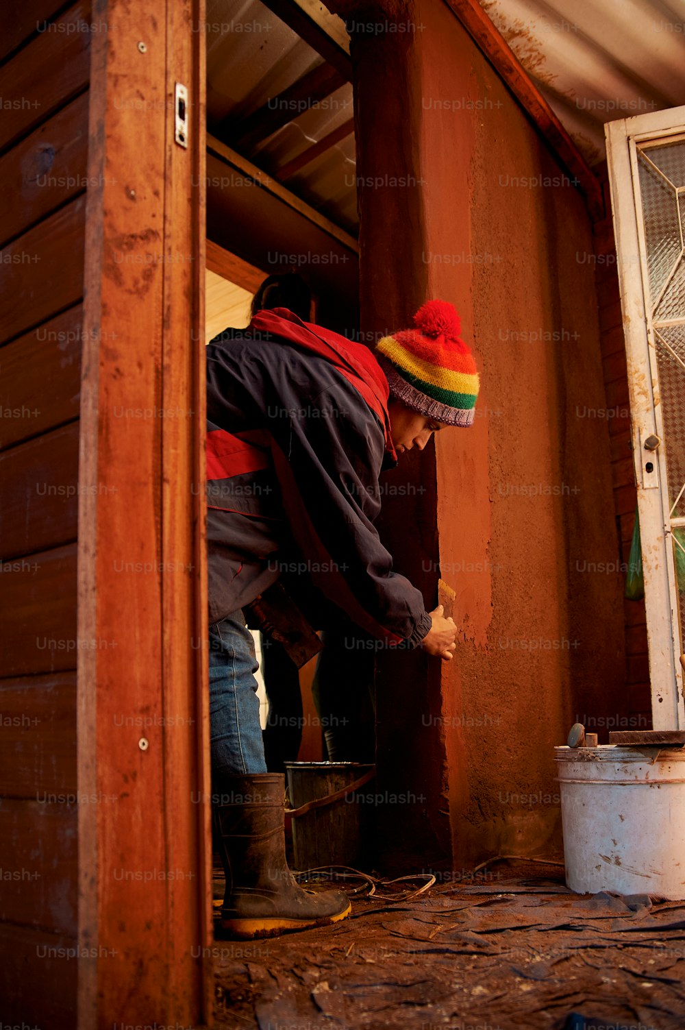 Um homem de chapéu vermelho, amarelo e verde está trabalhando em uma janela
