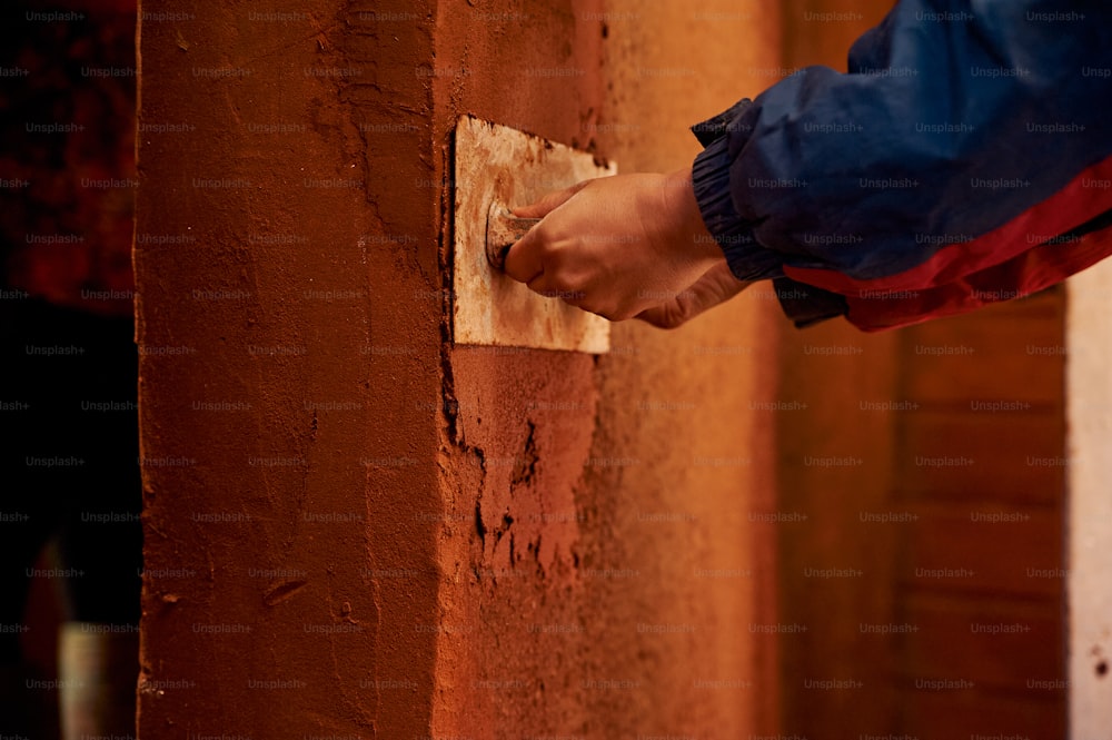 a person's hand on a wall with a piece of paper stuck to it