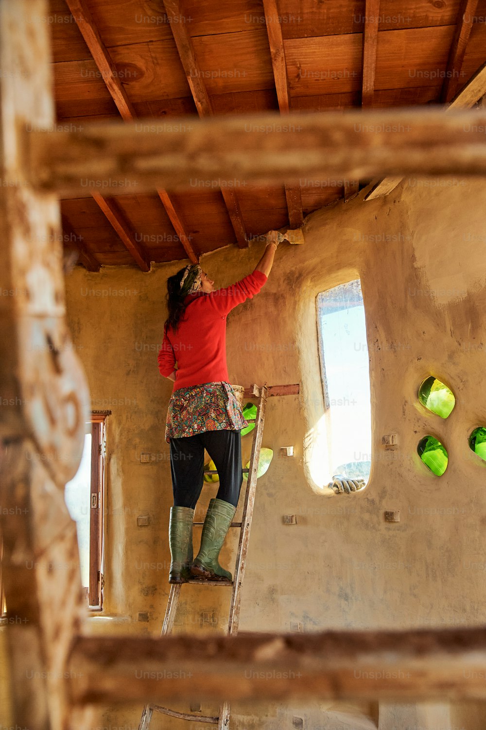 a woman standing on a ladder in a room