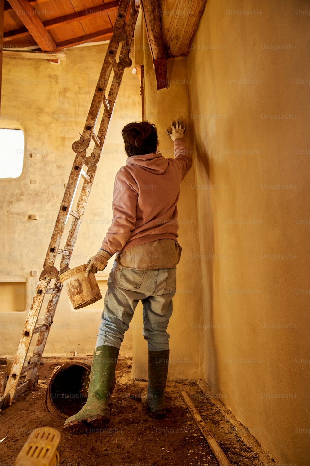 女性がはしごで壁を描いている