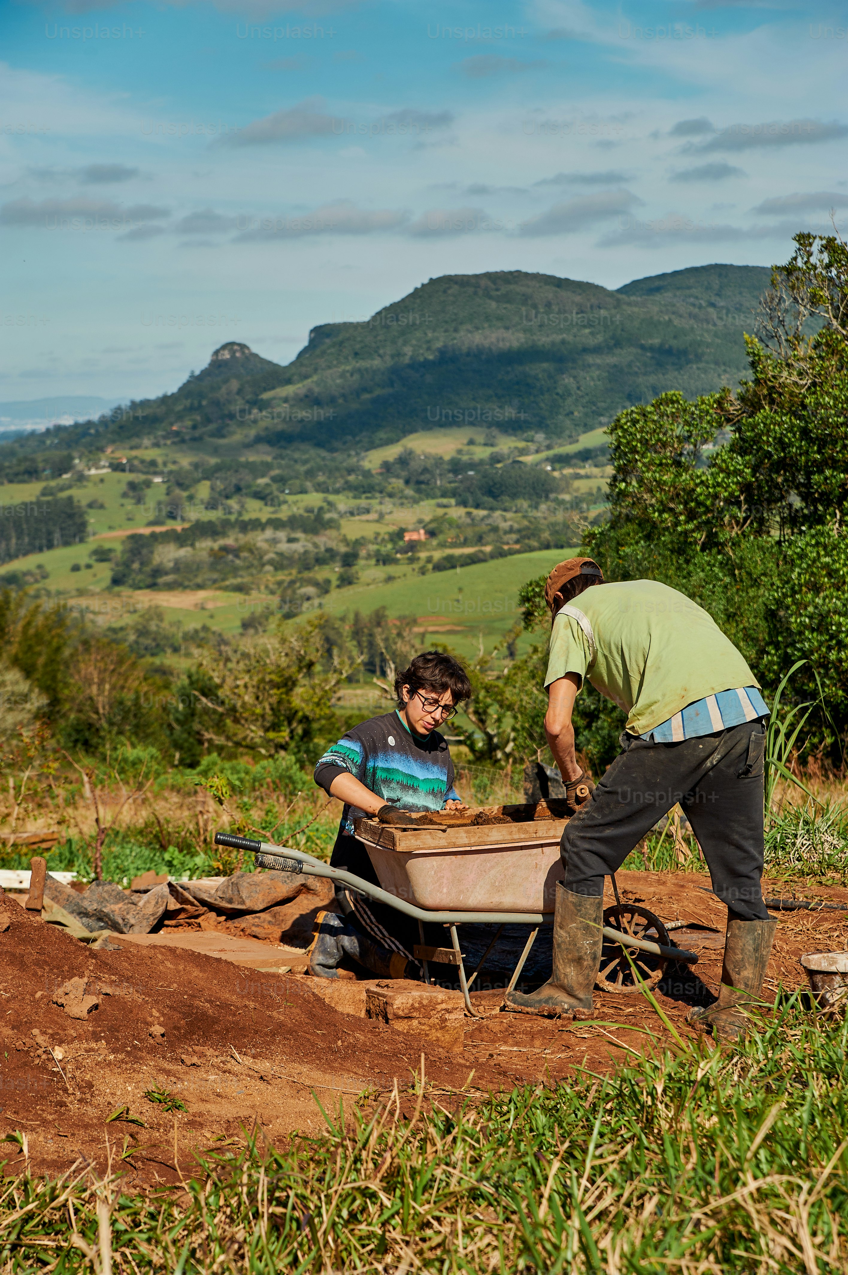 a man pushing a wheelbarrow with another man pushing a wheelbarrow